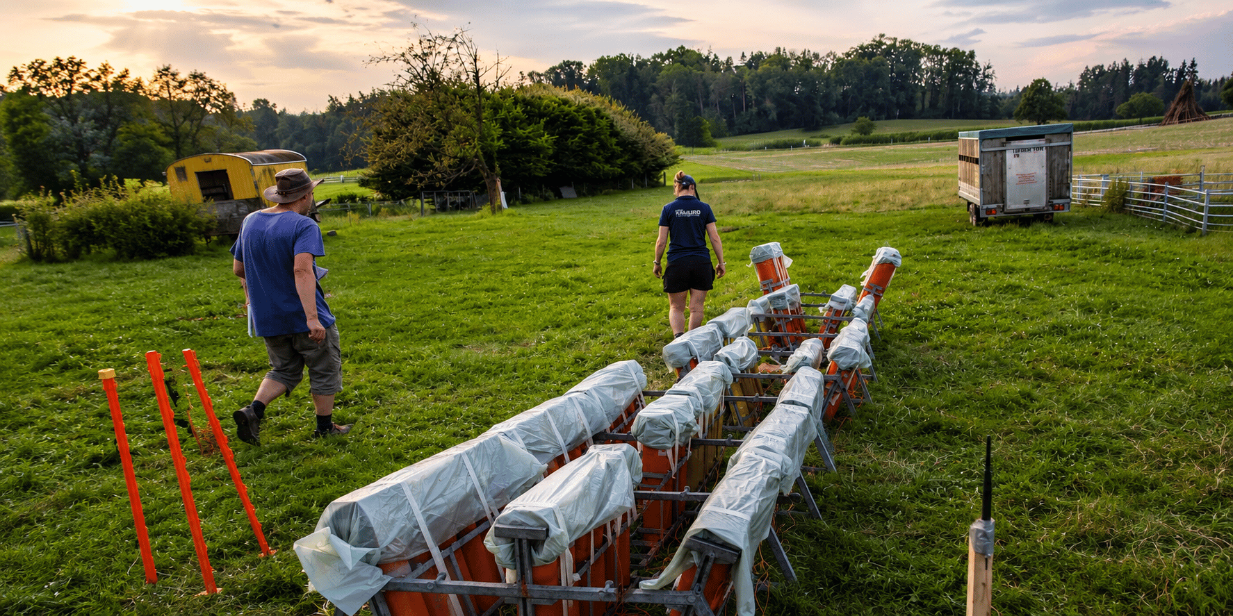 Mitglieder des Kamuro Feuerwerksvereins bereiten ein professionelles Grossfeuerwerk auf einer Wiese vor und richten die Feuerwerksgestelle für eine sichere Durchführung aus.